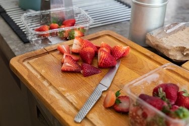 Chopped strawberries on a kitchen bench with a kitchen knife