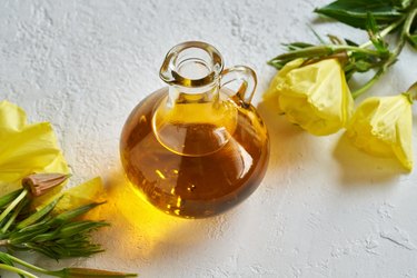 A bottle of evening primrose oil, a food high in GLA, with blooming evening primrose plant