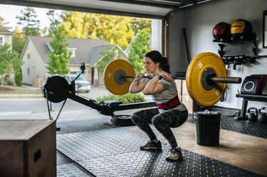 woman performing front squat with the best weight lifting equipment in home gym in garage