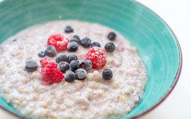 Oatmeal in a teal bowl with currants and raspberries as an example of a breakfast for gout