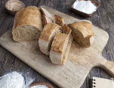 Wheat bread on wooden platter with bowls of flour to show pics of celiac rash, coeliac eyes and gluten face before and after flour in eyes