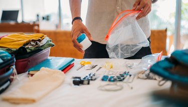 A man's hand packs cosmetics and medicines for a flight