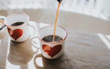 Two cups of coffee with maple syrup in white mugs with red hearts on the,m