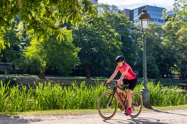 Person wearing a pink cycling jersey and black bike shorts riding a bike outside in a park