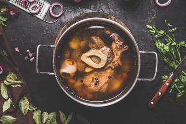 Beef bone broth or stock in cooking pot, view from above