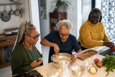 Three older Black women baking together at home in a kitchen