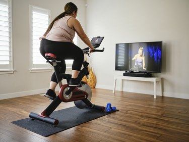 Person using magnetic resistance exercise bike at home in living room.
