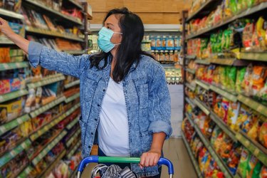 A woman wearing a face mask while shopping in an aisle of the grocery store