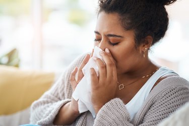 woman sneezing into a tissue