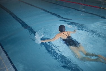 Active senior woman swimming breaststroke in indoor pool