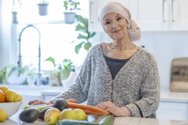 老女人戴头巾站在明亮的厨房