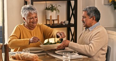An older adult couple sit down to enjoy a healthy meal together at home