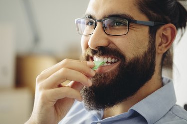 Smiling man eating green stick of chewing gum