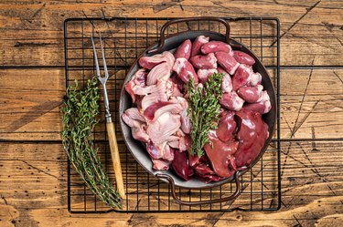 Raw bird giblets meat set, chicken offals, liver, hearts, gizzards Stomach. Wooden background. Top view