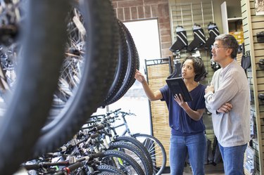 Sales team using digital tablet to calculate the cost of a used bikein bicycle shop