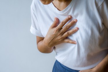 Person with hand holding their chest wearing a white t-shirt