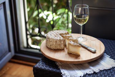 tyramine-rich aged goat cheese and wine on wooden table by patio