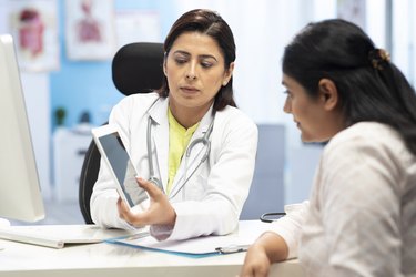 Doctor and patient are discussing at clinic showing report in computer, stock photo