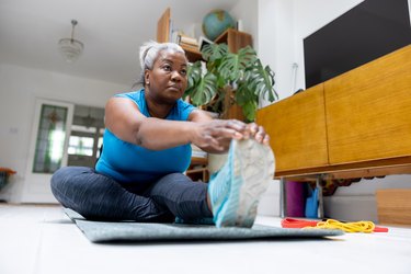 Older adult exercising with multiple sclerosis, doing stretching exercises at home