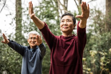 two older adults practice tai chi outdoors