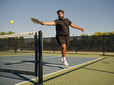 a young adult with a short afro in a larger body plays pickleball after doing pickleball exercises to get in shape