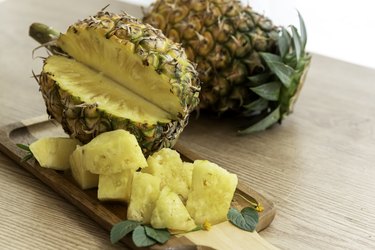 Fresh sliced pineapple on wooden tray on table