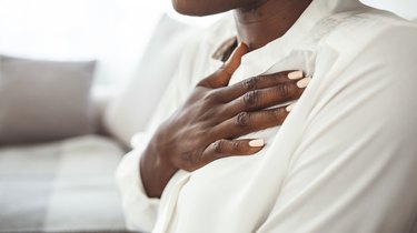 close view of a person wearing a white shirt with their hand on their chest because they have a crackling sound when breathing