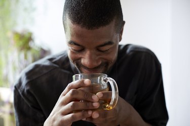 person holding glass mug of tea for health benefits for longevity