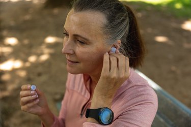 Female jogger putting headphone in her ear and wondering why her ears are itchy