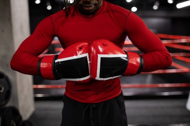Close-up image of person in a red long-sleeved shirt wearing red boxing gloves.