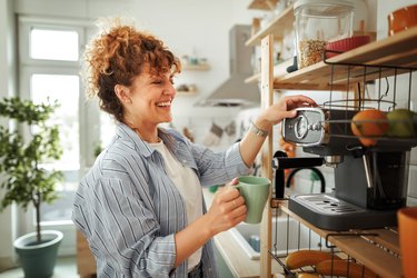 Young beautiful smiling woman making coffee in a domestic kitchen