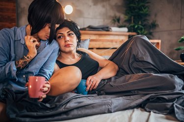 Lesbian couple drinking coffee in bed