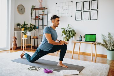 Person in blue T-shirt and black sweatpants doing mobility exercises in their living roo