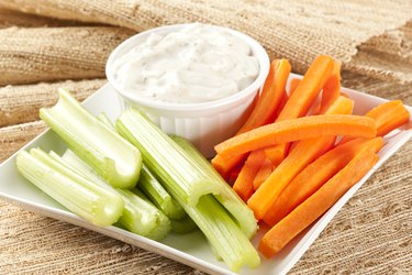 Container of ranch dressing with celery and carrot sticks