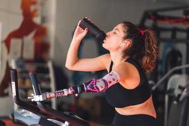 Person wearing black sports bra and leggings exercising on a stationary bike to demonstrate REHIT