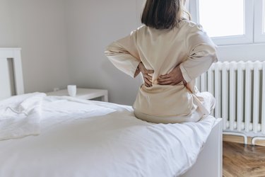 Woman feels back pain massaging aching muscles