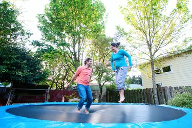 Two people jumping on a trampoline outside for fun