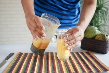 person pouring a blended smoothie into a glass following a diet for bowel adhesion symptoms