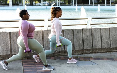 Two African-American woman doing lunges in city park