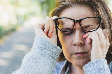 woman whose eyes are always red rubbing her eyes outdoors