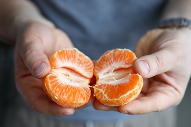 Close up shot of hands holding two halves of an orange for anti-inflammatory rash