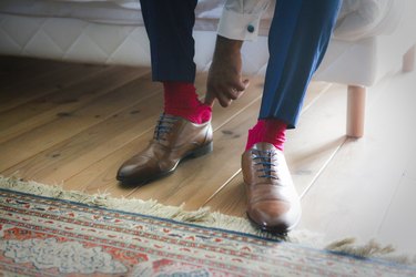 close view of a person putting dress shoes on their feet, and the shoes are snug because the person's feet have gotten bigger with age