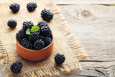 Ripe and sweet blackberries in bowl on wooden table