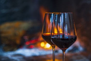 Two glasses of red wine in front of the fireplace fire