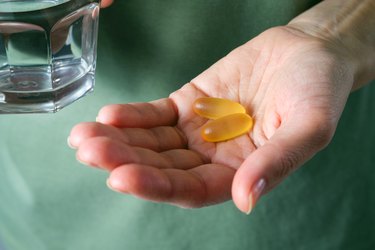 closeup of hand holding omega-3 fish oil capsules or medications