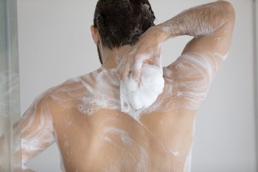 Man washing back with soap in the shower