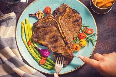 Hands cutting T-Bone Steak before getting meat sweats