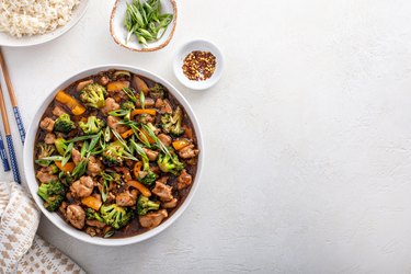 Chicken stir-fry with broccoli and sweet pepper in a white bowl on white table