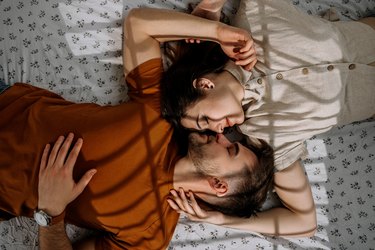 Close-up portrait of beautiful sensual young couple hugging while lying on bed