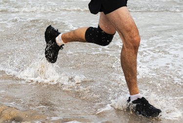 Legs of man running and splashing on edge of beach